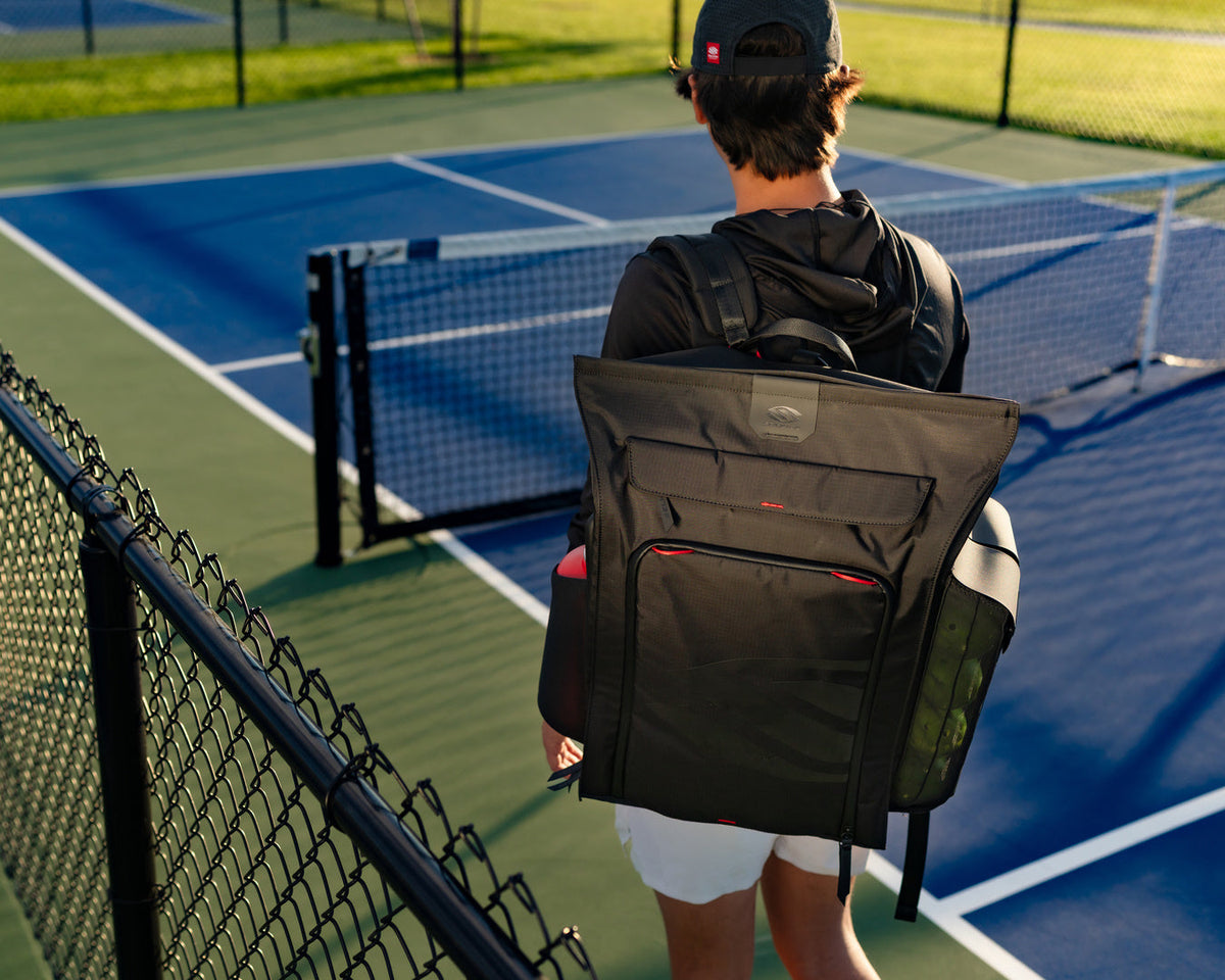 A man carrying a Pro Line 2.0 Tour Pickleball Backpack on a pickleball court