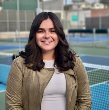 Brynn Grissom, a public relations associate at Selkirk Sport, smiling in front of pickleball courts.