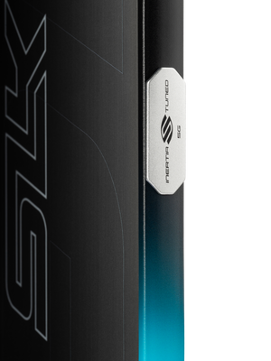 Close-up of a board edge with a metal badge reading 'INERTIA TUNED 5G' and a teal-to-black gradient finish.