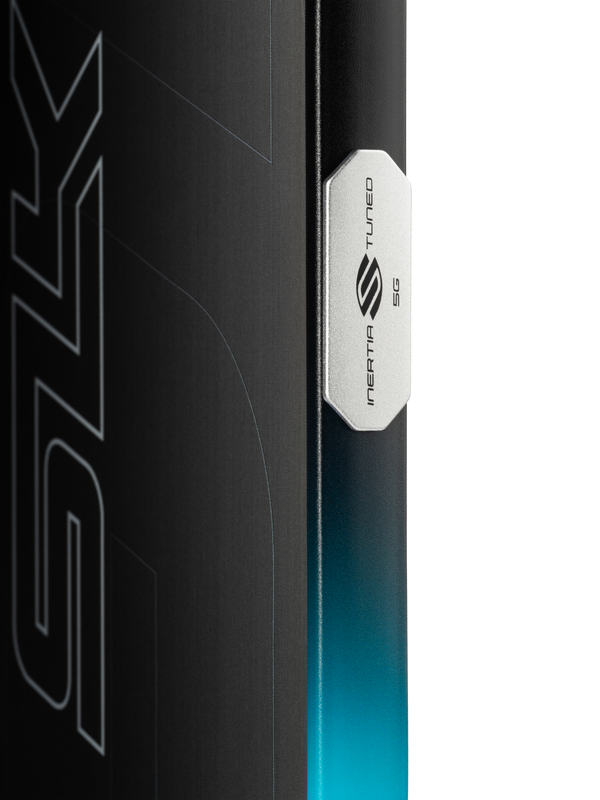 Close-up of a board edge with a metal badge reading 'INERTIA TUNED 5G' and a teal-to-black gradient finish.